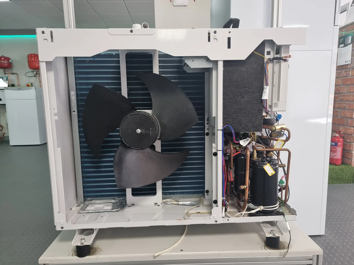 Air source heat pump outdoor unit with the casing removed for servicing, showing the fan, coil and compressor