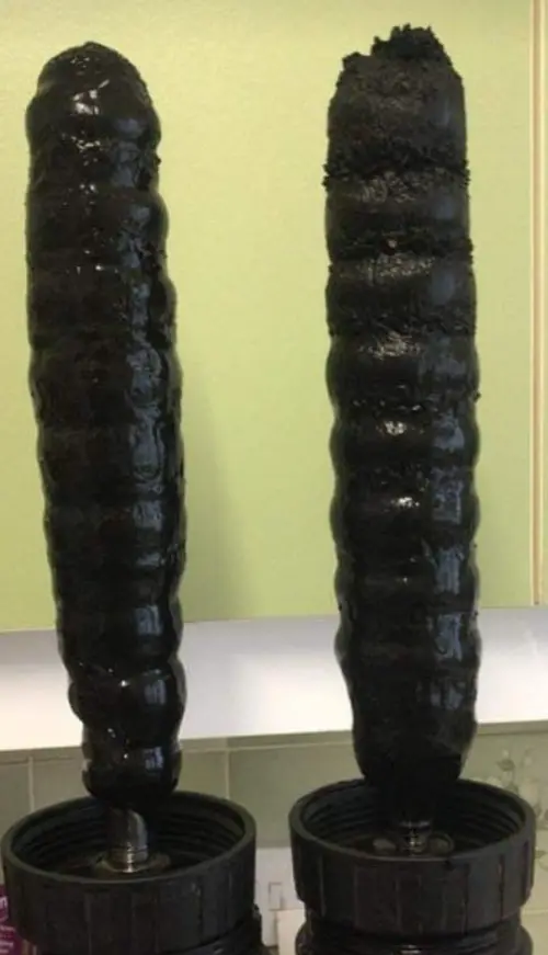 Two magnetic filter cores coated in black sludge taken out of a heating system