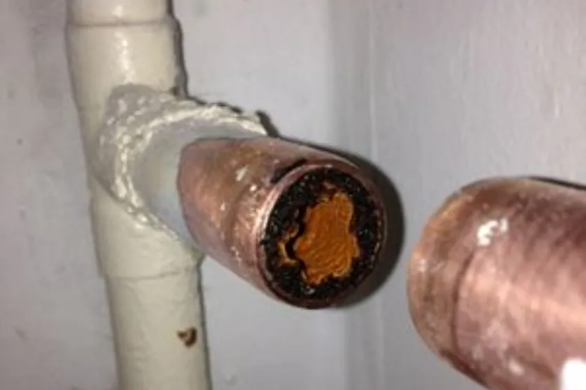 Heating pipe cut open showing a heavy build-up of black sludge