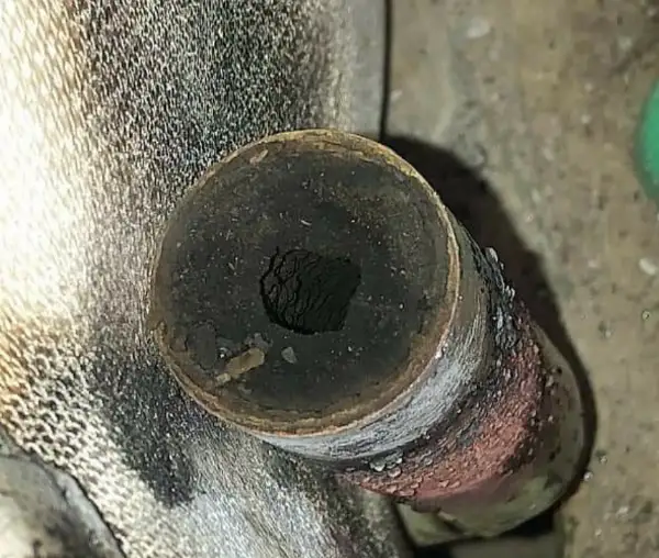 Heating pipe almost blocked by a build-up of black sludge